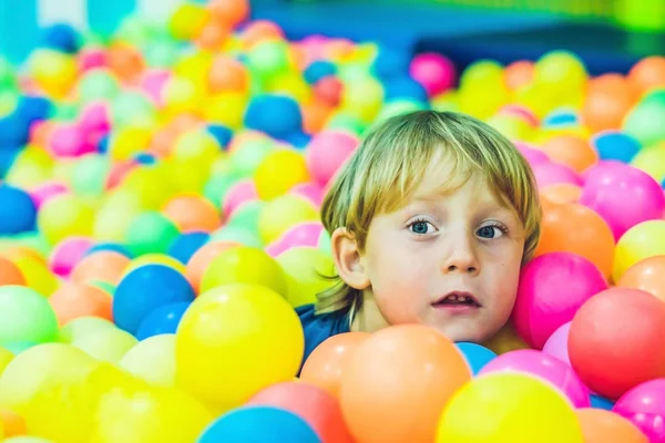 Niño niño feliz jugando en coloridas bolas de plástico patio vista alta. Divertido niño divirtiéndose en el interior — Foto de Stock