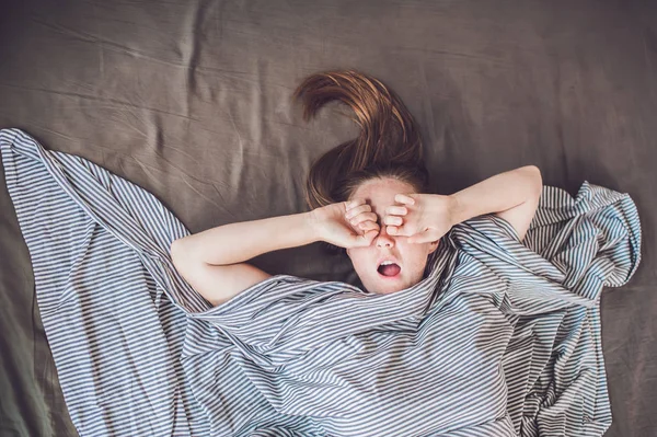 Beautiful young woman lying down in bed and sleeping, top view. Do not get enough sleep concept