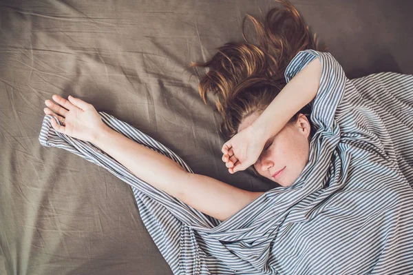 Wanita muda yang cantik berbaring di tempat tidur dan tidur, pandangan atas. Tidak mendapatkan konsep tidur yang cukup — Stok Foto