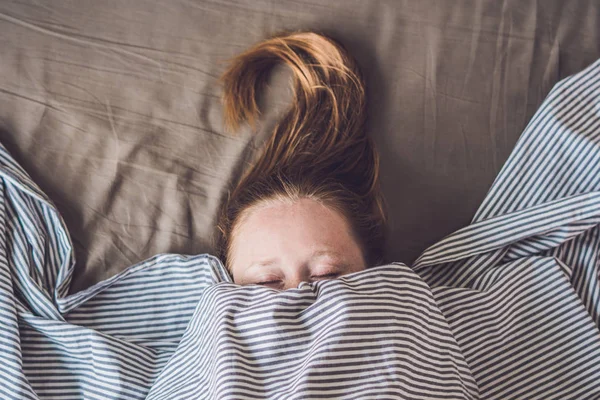 Wanita muda yang cantik berbaring di tempat tidur dan tidur, pandangan atas. Tidak mendapatkan konsep tidur yang cukup — Stok Foto