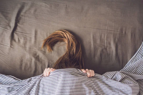 Wanita muda yang cantik berbaring di tempat tidur dan tidur, pandangan atas. Tidak mendapatkan konsep tidur yang cukup — Stok Foto