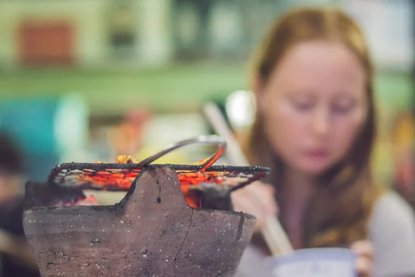 Menina fritando carne em uma pequena grelha em um restaurante — Fotografia de Stock