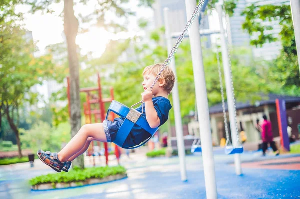 Little boy on a swing in the park. — Stock Photo, Image