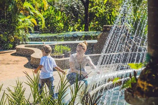 Mother with son playing in a fountain — Stock Photo, Image