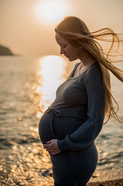 Donna incinta in piedi sulla spiaggia — Foto Stock