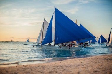 Gün batımında mavi yelkenli teknelerden,