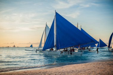 Gün batımında mavi yelkenli teknelerden,