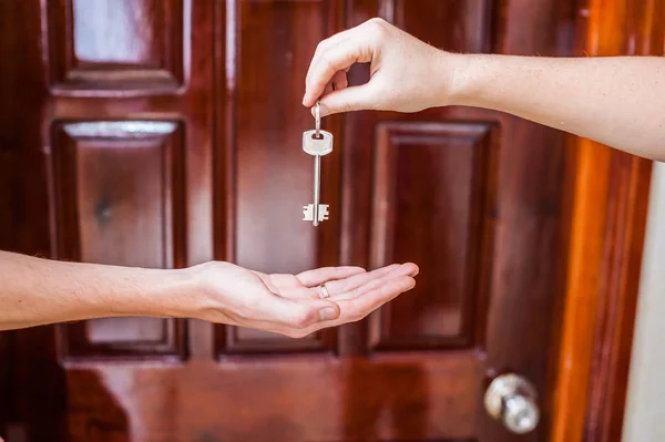 Mão feminina dando uma chave para a casa — Fotografia de Stock