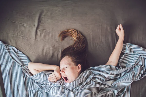 Young woman lying down in bed — Stock Photo, Image