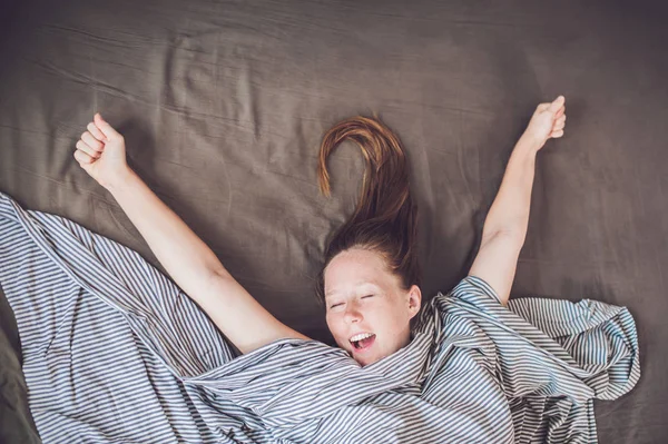 Молода жінка лежить в ліжку — стокове фото