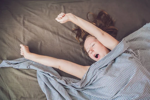 Wanita muda berbaring di tempat tidur — Stok Foto