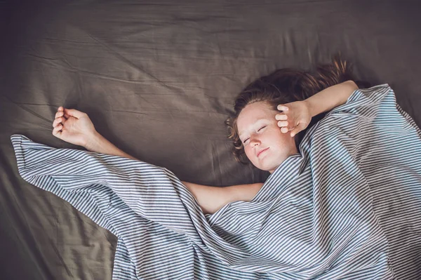 Νεαρή γυναίκα ξαπλωμένη στο κρεβάτι — Φωτογραφία Αρχείου