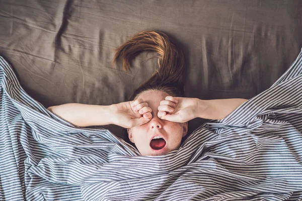 Young woman lying down in bed — Stock Photo, Image