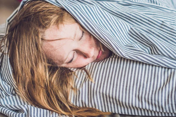 Young woman lying down in bed — Stock Photo, Image