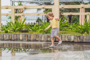 Küçük çocuk bir su birikintisi ile çalışır. 