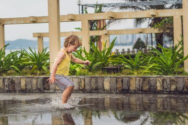 Küçük çocuk bir su birikintisi ile çalışır. 
