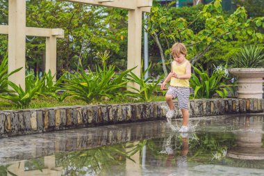 Küçük çocuk bir su birikintisi ile çalışır. 