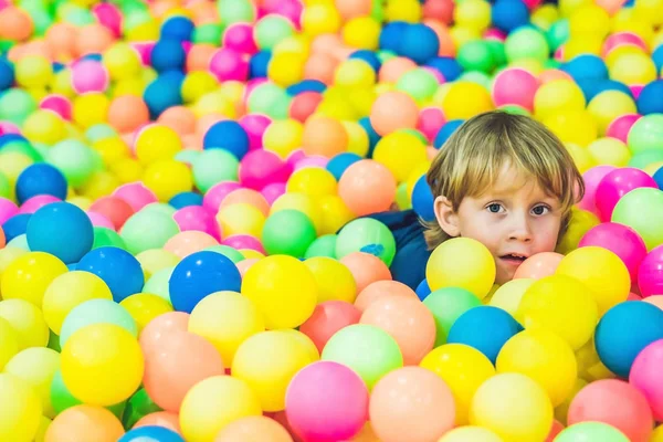 Boy playing at colorful plastic balls — Stock Photo, Image