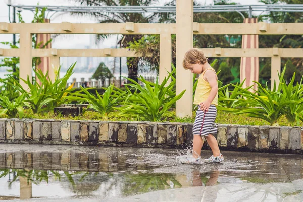 Pequeño niño corre a través de un charco . — Foto de Stock