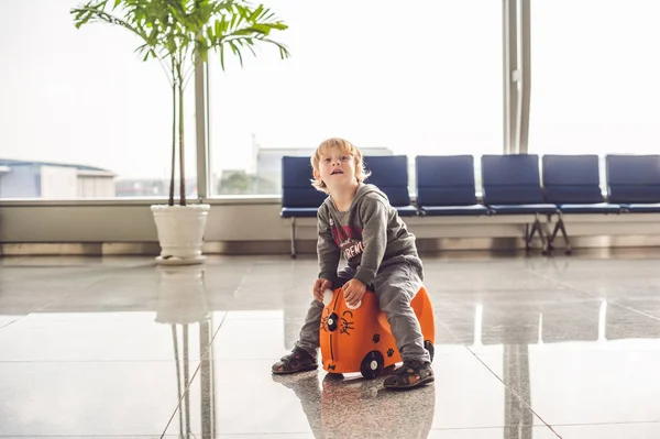 Netter kleiner Junge mit orangefarbenem Koffer — Stockfoto