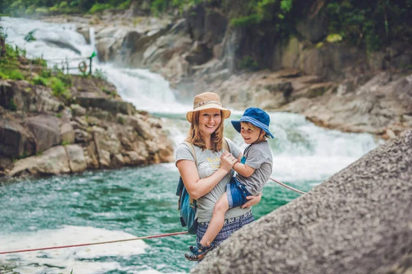 Matka a syn relaxační pod vodopádem. — Stock fotografie
