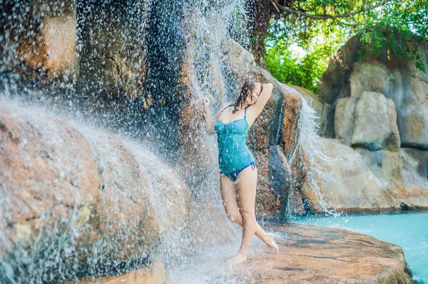 Woman relaxing under a waterfall in aquapark — Stock Photo, Image