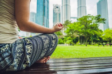 Genç bir kadın parkta meditasyon yapıyor.