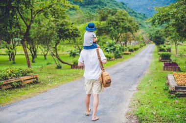 Baba ve oğul manzaralı bir yolda yürürken