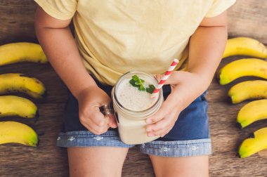 Bir muz smoothie tutan çocuk