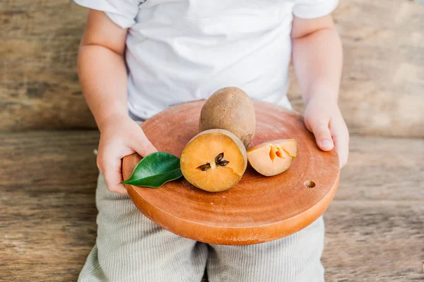 Manos con frutas frescas de sapodilla — Foto de Stock