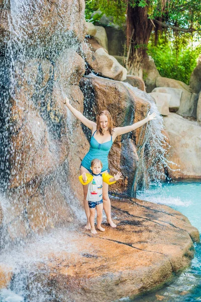 Madre e hijo relajándose bajo una cascada — Foto de Stock