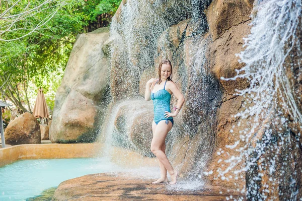 Woman relaxing under a waterfall in aquapark — Stock Photo, Image