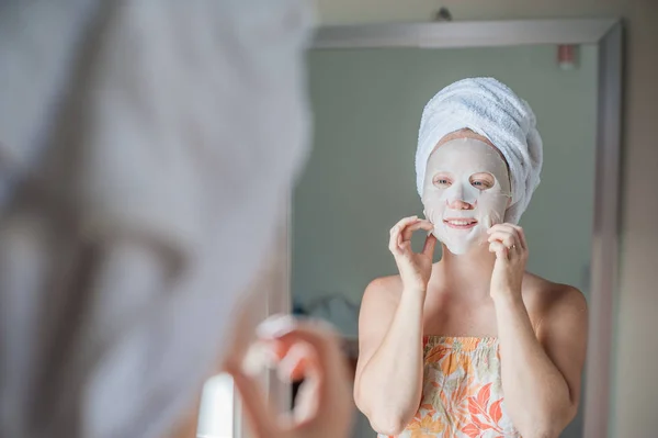 Donna che fa foglio maschera facciale — Foto Stock