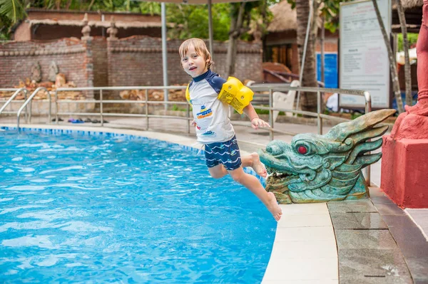 boy jump into the water of swimming pool.