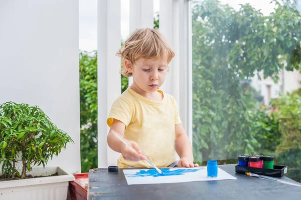 Маленький мальчик рисует красочными красками — стоковое фото