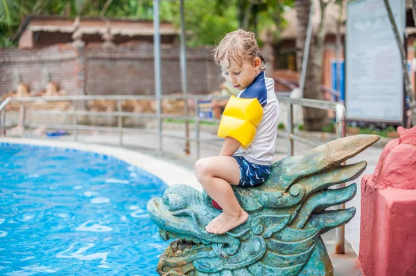 Niño se sienta en la estatua asiática — Foto de Stock
