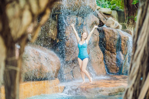 Nainen rentoutumassa vesiputouksen alla vesipuistossa — kuvapankkivalokuva