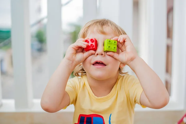 Menino faz olhos de blocos infantis coloridos — Fotografia de Stock