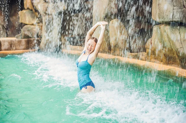 Frau entspannt sich unter einem Wasserfall im Aquapark — Stockfoto