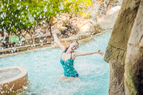 Vrouw ontspannen onder een waterval in het aquapark — Stockfoto