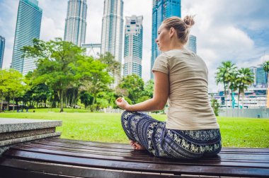 Genç bir kadın parkta meditasyon yapıyor. 