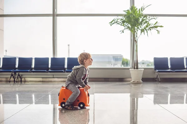 Симпатичный маленький мальчик с оранжевым чемоданом — стоковое фото