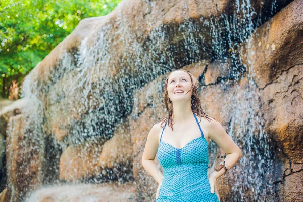 Vrouw ontspannen onder een waterval in het aquapark — Stockfoto