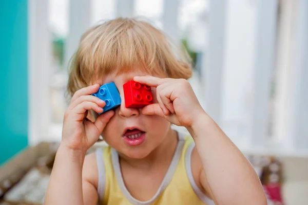 Boy makes eyes of colorful children 's blocks — стоковое фото