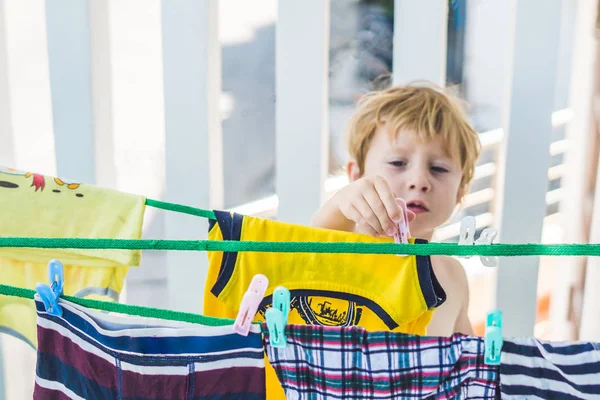 little boy hanging up clothes