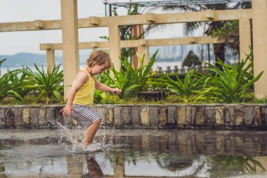 Küçük çocuk bir su birikintisi ile çalışır. 