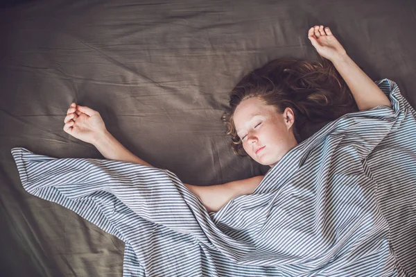 Νεαρή γυναίκα ξαπλωμένη στο κρεβάτι — Φωτογραφία Αρχείου