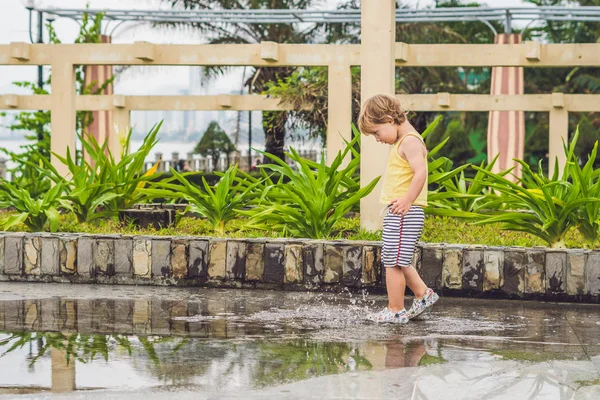 Kleiner Junge läuft durch eine Pfütze. — Stockfoto