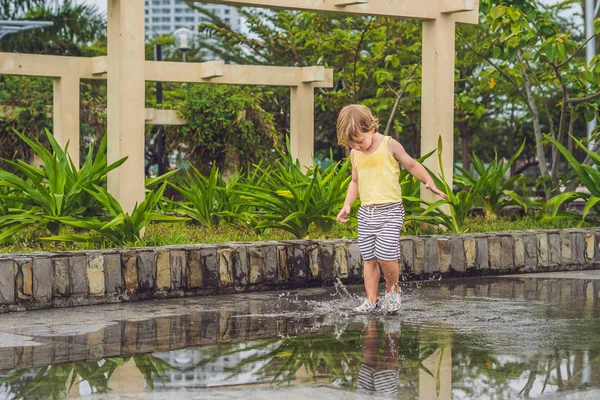 Little boy runs through a puddle. — Stock Photo, Image