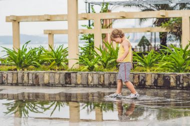 Küçük çocuk bir su birikintisi çalışan. 